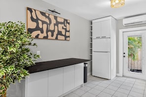 A modern kitchen with white cabinets, a black countertop, a large abstract painting, and a potted plant. - 15 min to Beach | 2 Queen Beds | Free Parking (U4) (Miami)