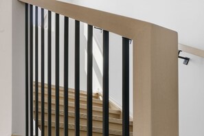 Una escalera con balaustres negros y paredes color beige.