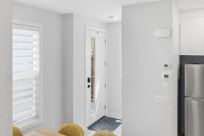 A modern kitchen with a stainless steel refrigerator, a door with a window, and a wall-mounted thermostat. - Beautiful 3BR Getaway in Trendy NW Calgary (Calgary)