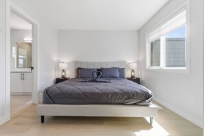 A modern bedroom with a bed, bedside tables, and a window. - Beautiful 3BR Getaway in Trendy NW Calgary (Calgary)
