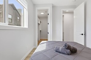 A bedroom with a bed, a window, and a door leading to a hallway. - Beautiful 3BR Getaway in Trendy NW Calgary (Calgary)