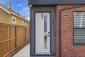 A modern building with a grey door, a brick wall, and a wooden fence. - Beautiful 3BR Getaway in Trendy NW Calgary (Calgary)