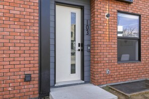 A building with a white door, brick walls, and a window. - Stylish Family Home • 3BR + 2.5 Bath • NW Calgary (Calgary)