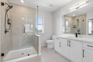 A modern bathroom with a glass-enclosed shower, a large mirror, white cabinets, and a toilet. - Stylish Family Home • 3BR + 2.5 Bath • NW Calgary (Calgary)