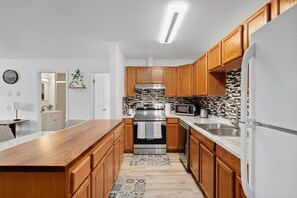 A modern kitchen with wooden cabinets, stainless steel appliances, and a tiled backsplash.