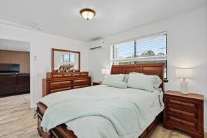 Ein Schlafzimmer mit Bett, Schminktisch, Nachttisch und einem großen Spiegel.