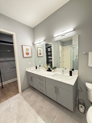 A modern bathroom with a double sink vanity, a large mirror, and a walk-in closet. - Luxury Modern King Bed Heart of Downtown Dallas (Dallas)