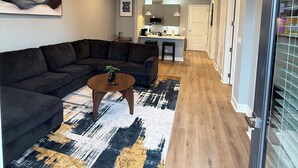 A modern living room with a sectional sofa, a coffee table, and a ceiling fan. - Luxury Modern King Bed Heart of Downtown Dallas (Dallas)