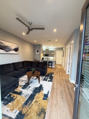 A modern living room with a sectional sofa, a coffee table, and a ceiling fan.