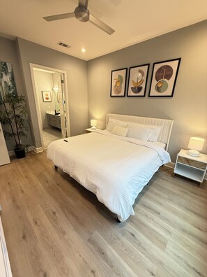 A bedroom with a bed, bedside tables, a ceiling fan, and wall art.