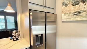 A modern kitchen with a stainless steel refrigerator, a built-in water dispenser, and a pendant light. - Luxury Modern King Bed Heart of Downtown Dallas (Dallas)