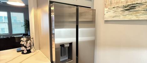 A modern kitchen with a stainless steel refrigerator, a built-in water dispenser, and a pendant light.