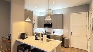 A modern kitchen with a central island, pendant lights, and a stainless steel range hood. - Luxury Modern King Bed Heart of Downtown Dallas (Dallas)