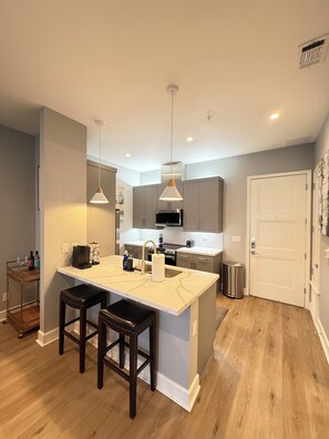 A modern kitchen with a central island, pendant lights, and a stainless steel range hood.