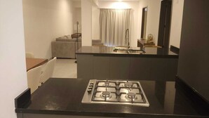 A modern kitchen with a gas stove, a dining area with a table and chairs, and a living room with a sofa and curtains. - Suites Santa Isabella (Ajijic)