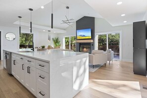 A modern kitchen with a large island, built-in appliances, and a fireplace. - Sleep 22, private pool, pickleball ct, hot tub (Sunrise Beach)
