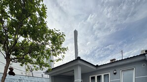 Una casa con un patio piastrellato, una zona relax coperta e un piccolo tavolo con sedie.