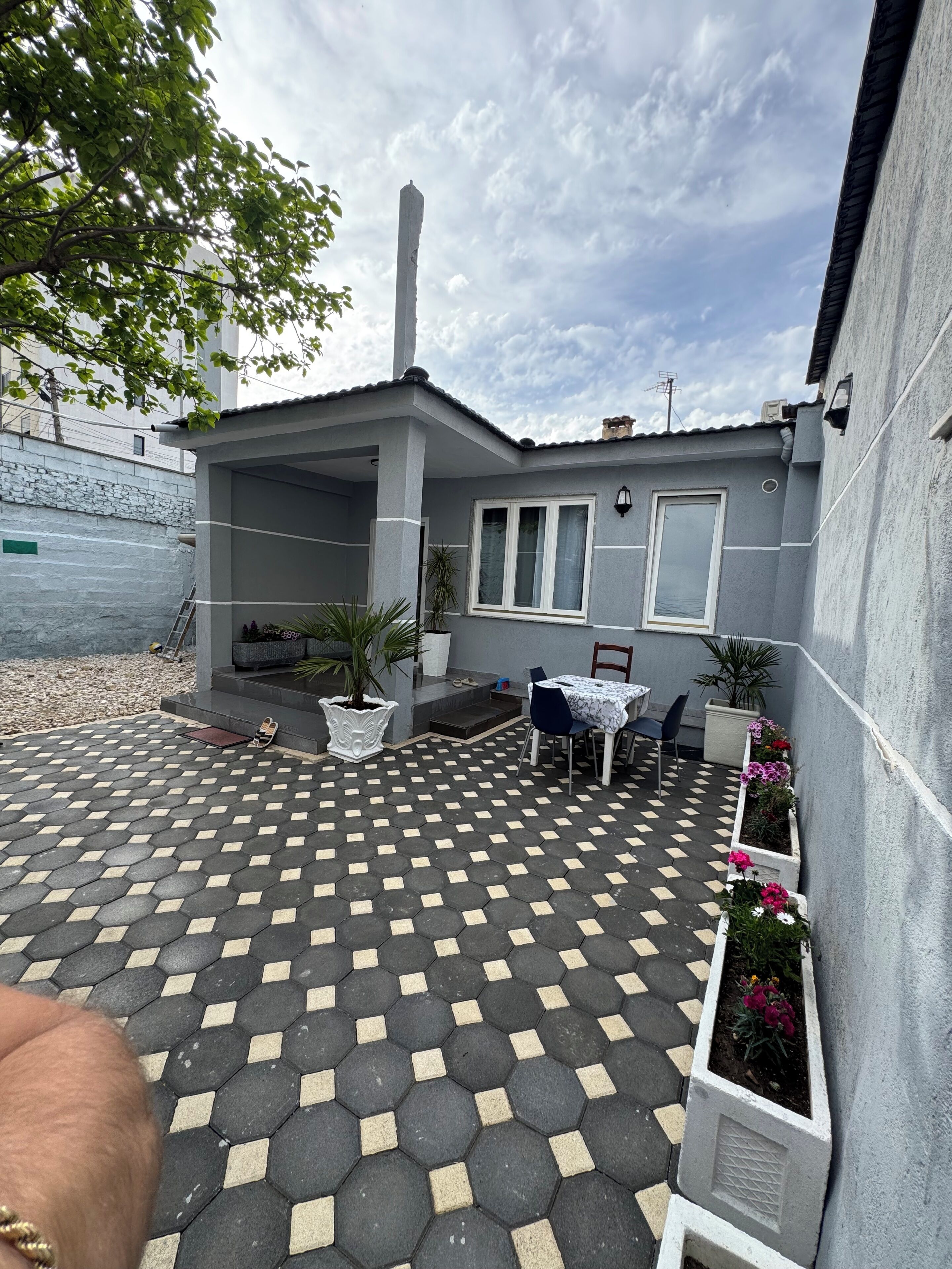 A courtyard with a tiled floor, a covered seating area, and potted plants.