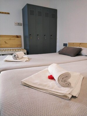 Ein Hotelzimmer mit zwei Betten, einem Holzkopfstück, einem Kleiderschrank und einer Holzwandverkleidung.