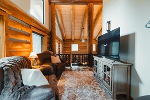 Ein Holzhütten-Interieur mit einer Couch, einem Fernseher und Holzwänden.
