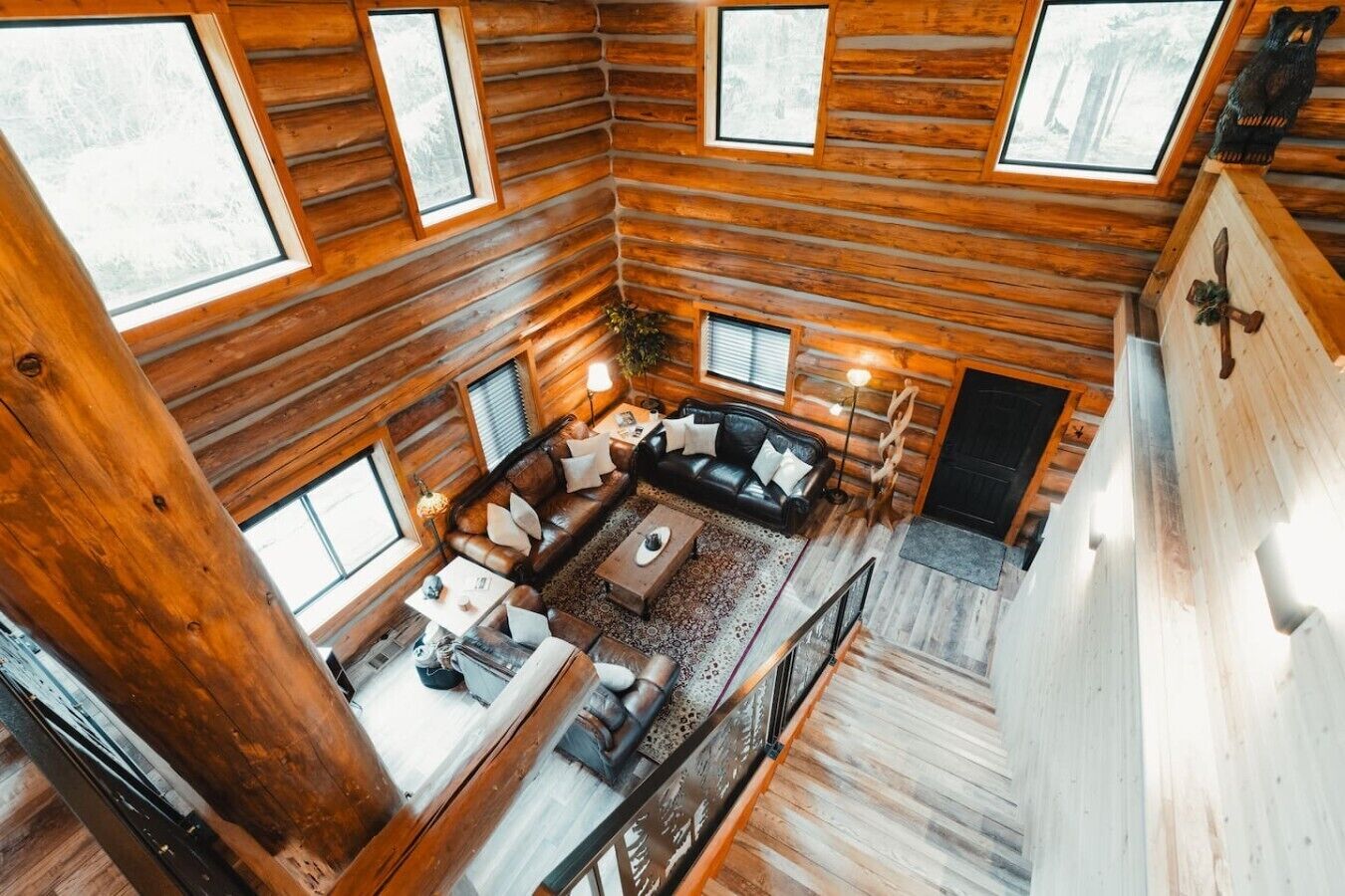 L’intérieur d’une cabane en rondins présente un espace de vie comprenant un ensemble de canapés, une table basse et une cheminée.