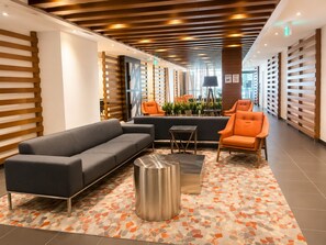 A modern lobby with a sofa, armchairs, a coffee table, and a patterned floor. - FIFA unobstructive view CN TOWER lakeshore 1+1(den) 2b1b condo with parking (Toronto)