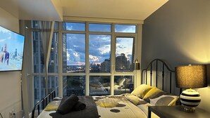 A bedroom with a large window, a bed, a desk, and a chair. - FIFA unobstructive view CN TOWER lakeshore 1+1(den) 2b1b condo with parking (Toronto)