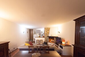 A living room with a fireplace, a dining area, and a kitchen in the background.