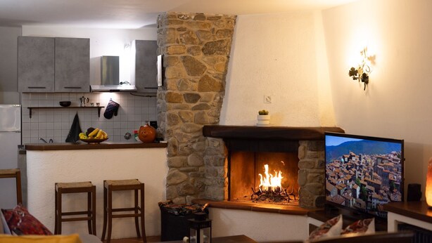 Una cucina con parete in pietra, camino e televisore che mostra una vista cittadina.