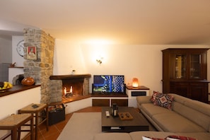A living room with a stone fireplace, a television, a sofa, and a cabinet.
