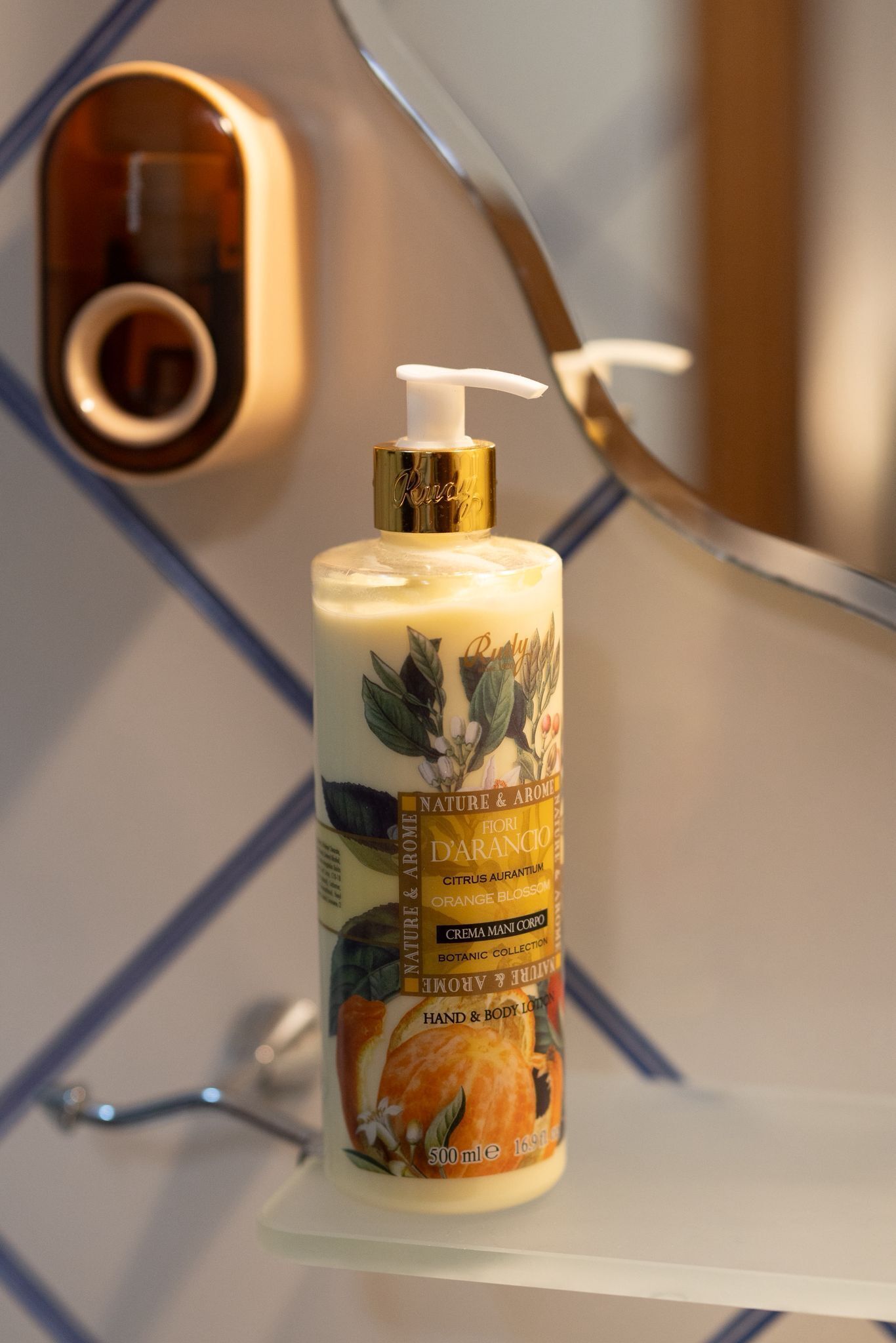 Une bouteille de lotion pour le corps est posée sur une étagère blanche, avec un mur au motif géométrique en arrière-plan.