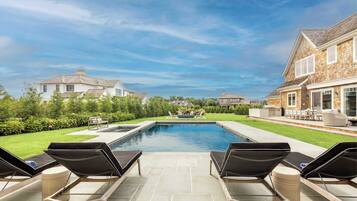 A swimming pool with lounge chairs, a patio area, and a view of surrounding houses.