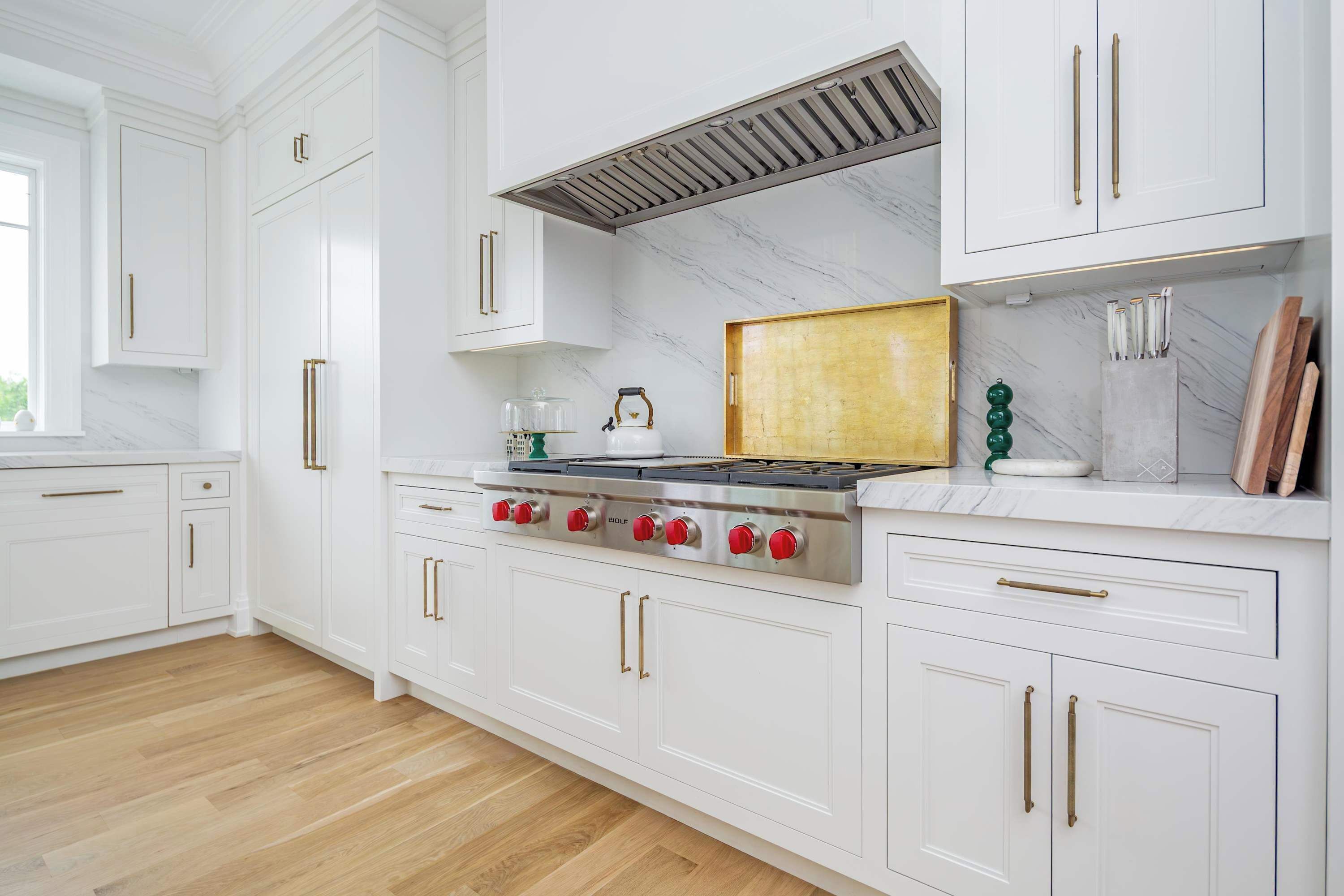 A kitchen with white cabinets, a stainless steel stove, and a marble backsplash.