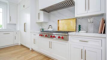 A kitchen with white cabinets, a stainless steel stove, and a marble backsplash.