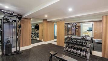 A gym with exercise equipment, mirrors, and wooden paneling.