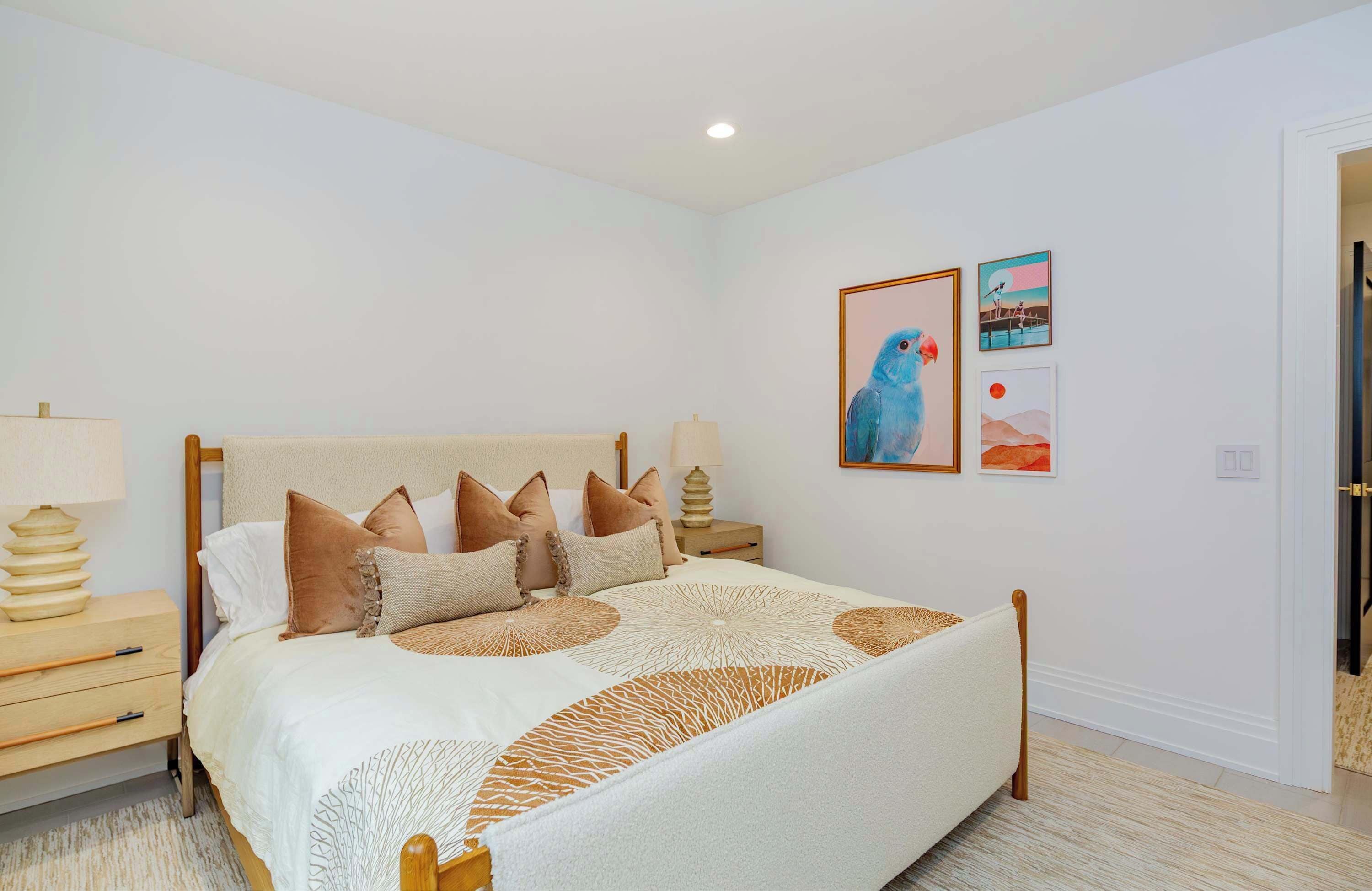 A bedroom with a bed, nightstands, and wall art.