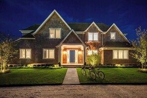 A two-story house with a well-maintained lawn, a pathway leading to the front door, and a bicycle parked outside.