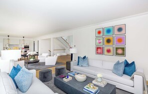 A modern living room with a sofa, coffee table, and artwork on the wall. - Rosko Estate by Rove Travel Villa With Pool &court (Southampton)