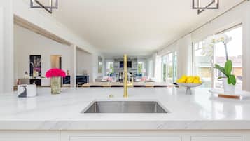 A modern kitchen with a central island, a large window, and a view of the outdoors.