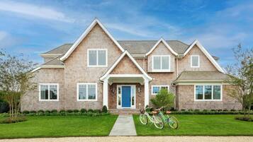 A two-story house with a front porch, a driveway, and a bicycle parked outside.