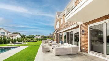 A modern house with a patio, outdoor furniture, and a swimming pool.
