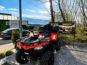 An ATV parked in a gravel area with a sign advertising quad bike rentals.