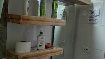 Et badeværelse med en hvid vask, træhylder og toiletartikler.