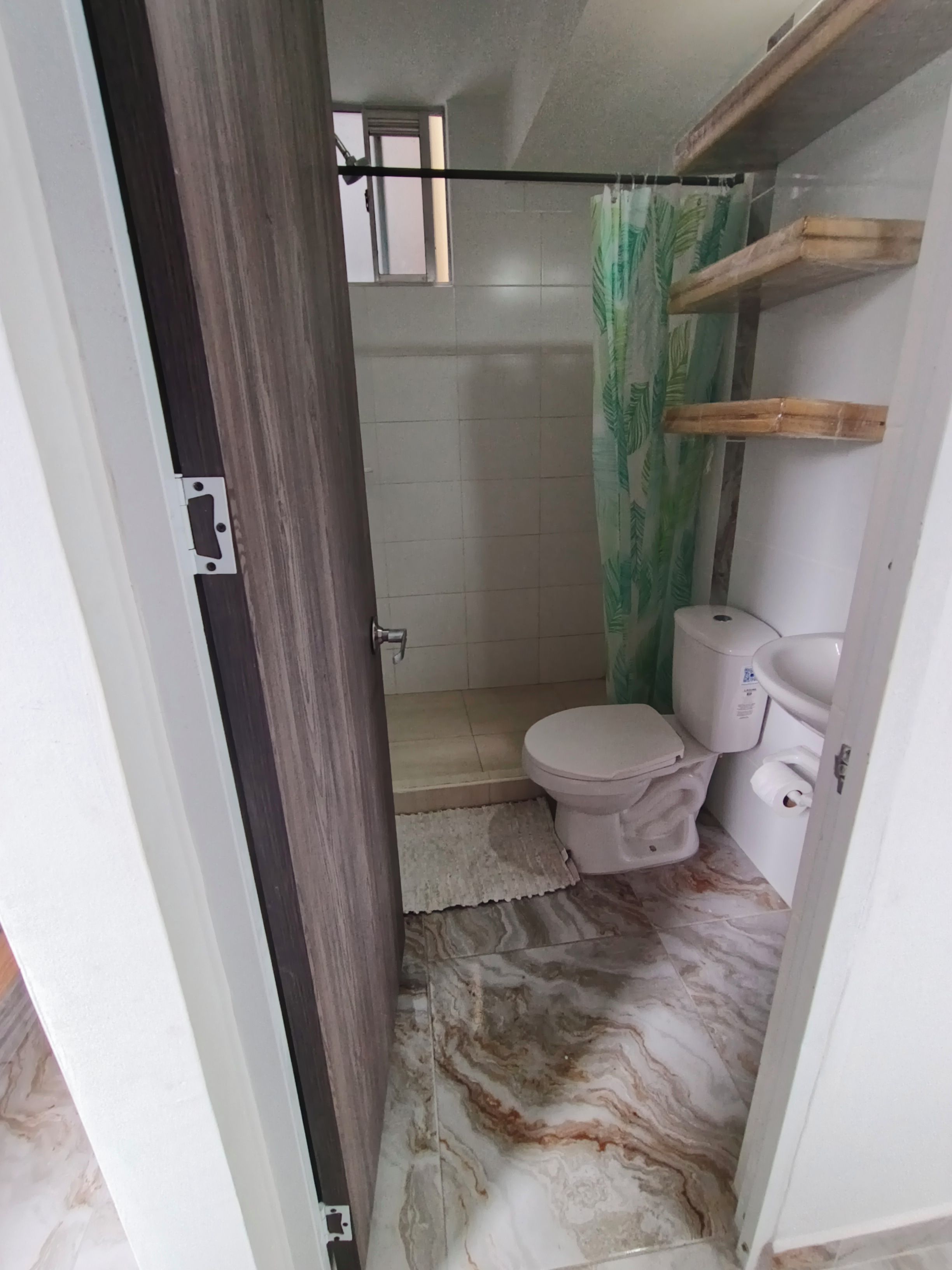 A bathroom with a toilet, a shower area, and a marble floor.
