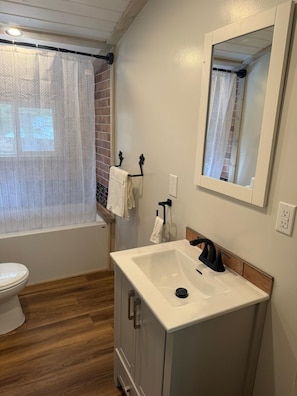 Un baño con inodoro, lavabo, espejo, toallero y cortina de ducha.