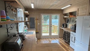 A wooden interior with a kitchen area, including a refrigerator, microwave, and a coffee machine. - Private Cariboo Retreat -House & Cabin Lakes, Fishing, Hunting ,Trails, Outdoor (Forest Grove)