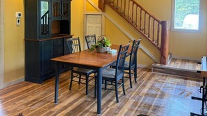 A dining area with a wooden table, chairs, a ceiling fan, and a staircase. - Private Cariboo Retreat -House & Cabin Lakes, Fishing, Hunting ,Trails, Outdoor (Forest Grove)