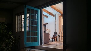 Une pièce avec une fenêtre à cadre bleu, un escalier menant à un niveau supérieur et une plante au premier plan.