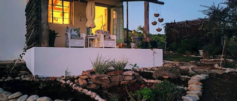 A house with a porch, outdoor seating, and a garden with a rock border.