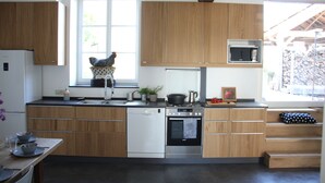 Una cocina moderna con armarios de madera, lavavajillas, horno, microondas y una ventana con vistas al exterior.